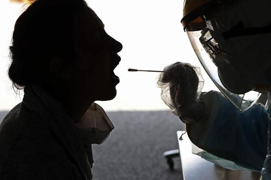 A nucleic acid test for the coronavirus using a throat swab is conducted on an inbound traveler upon arrival in Shanghai at a testing site in Changning district on Monday. (YIN LIQIN/CHINA NEWS SERVICE)