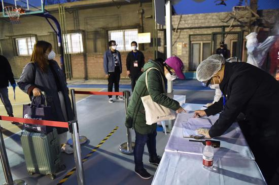 A woman returning from Hubei (2nd L, front) gets her information checked at a gathering point in Dongcheng District in Beijing, capital of China, March 25, 2020. (Xinhua/Chen Zhonghao)