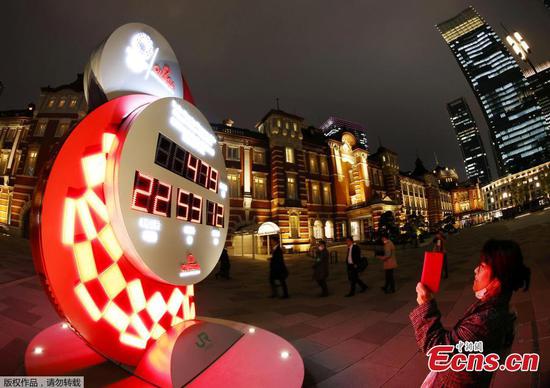 A passerby takes photos of a countdown clock showing the adjusted days and time for the start of the postponed Tokyo Olympic Games, which are now set to begin on July 23, 2021, in front of Tokyo station, in Tokyo March 30, 2020. (Photo/Agencies)