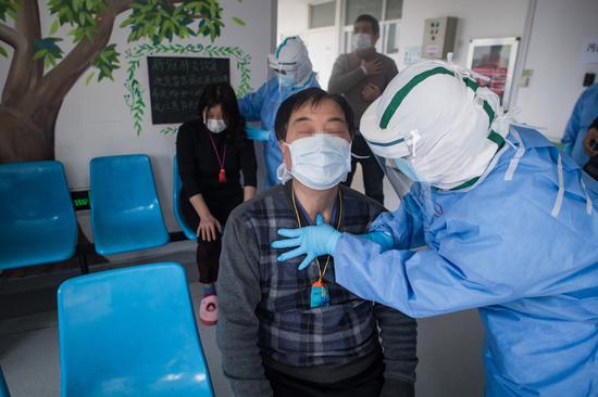 A medical worker teaches a patient who contracted the novel coronavirus pneumonia to do acupressure massage to help him recover at the Wuhan pulmonary hospital in Wuhan, Hubei province, March 19, 2020. (Photo/Xinhua)