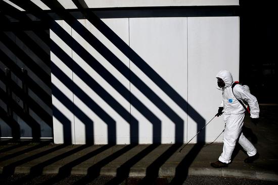 A municipal worker disinfects the street to stop the spread of the COVID-19 in Cascais, Portugal, March 28, 2020. (Photo by Pedro Fiuza/Xinhua)