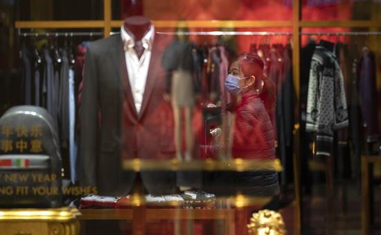 A sales clerk arranges clothes inside a shop in a shopping mall in Wuhan, central China's Hubei Province, March 30, 2020. (Xinhua/Fei Maohua)