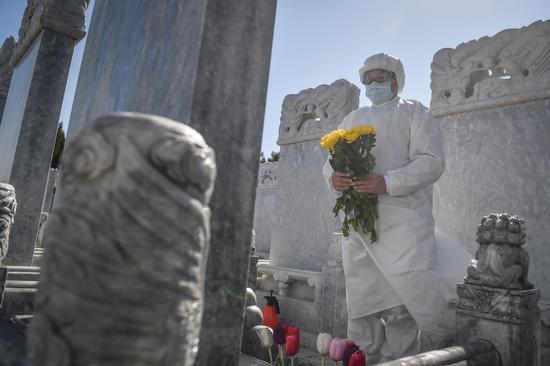 A cemetery staff member offers flowers to the deceased at the Babaoshan People's Cemetery in Beijing, capital of China, March 28, 2020. (Xinhua/Peng Ziyang)