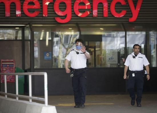 Security guards walk outside the emergency entrance of Vancouver General Hospital in Vancouver, Canada, April 1, 2020. (Photo by Liang Sen/Xinhua)