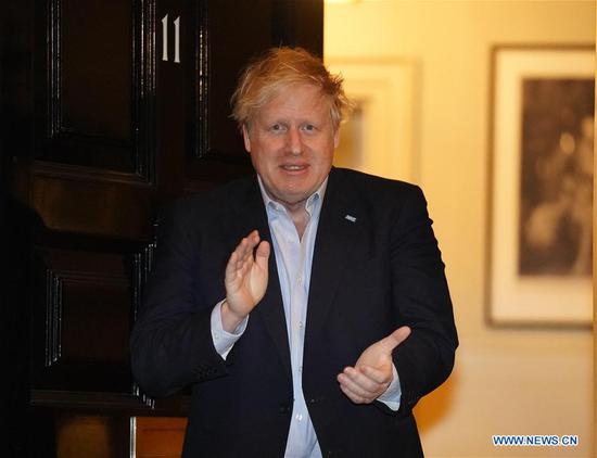 File photo taken on April 2, 2020 shows British Prime Minister Boris Johnson clapping for National Health Service staff outside 11 Downing Street in London, Britain.  (Pippa Fowles/No 10 Downing Street/Handout via Xinhua)