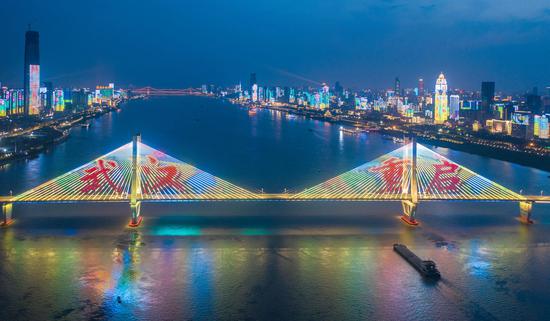 A light show was staged on the No. 2 Wuhan Yangtze River Bridge and along banks of the Yangtze River in Wuhan, April 6, 2020, to celebrate the upcoming lifting of lockdown of the city. (Photo/China News Service)