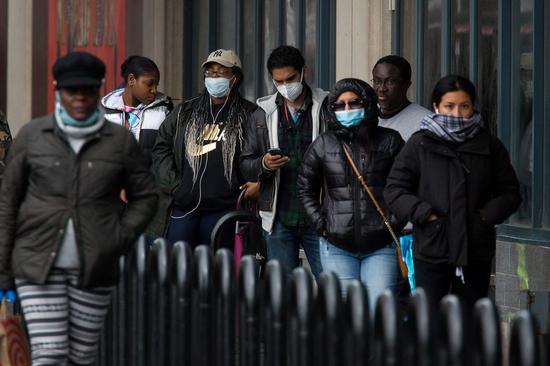 People wearing face masks wait in line outside a grocery store in the Brooklyn borough of New York, the United States, on April 3, 2020. (Photo by Michael Nagle/Xinhua)