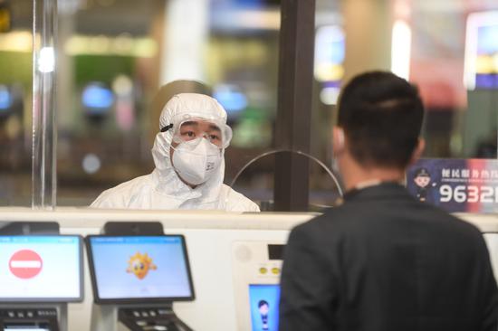 A police officer talks to a passenger at Xiaoshan International Airport in Hangzhou, Zhejiang province, on March 13, 2020. [Photo/Xinhua]
