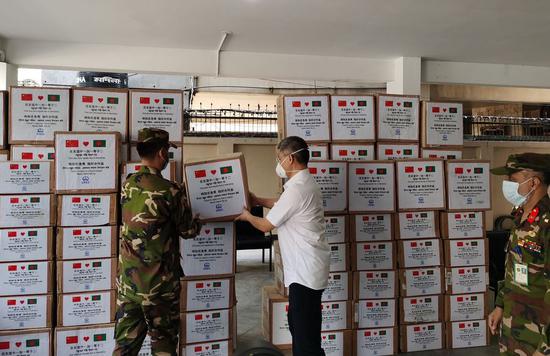 Wang Kun, China Railway Group limited (CREC)'s representative in Bangladesh, hands over donation of medical supplies to an official of a military-run hospital in Dhaka, Bangladesh on April 7, 2020. (Str/Xinhua)