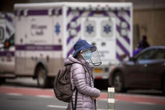 A woman wearing face protection walks near NYU Langone Medical Center during the coronavirus pandemic in New York, the United States, April 8, 2020. (Photo by Michael Nagle/Xinhua)