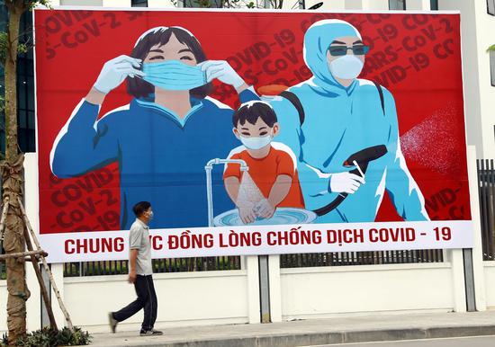 A man walks past a COVID-19 fight poster in the capital city of Hanoi, Vietnam, April 1, 2020. Vietnamese Prime Minister Nguyen Xuan Phuc signed a decree on Wednesday to declare COVID-19 a nationwide epidemic in Vietnam, according to the country's government website. (VNA/Handout via Xinhua)