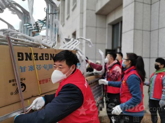 Volunteers transport furniture for a temporary hospital in Suifenhe, Heilongjiang province, on Saturday. The facility has 580 beds for COVID-19 patients. (Photo/China News Service)