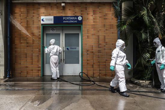 Staff members conduct disinfection at the Clinicas Hospital in Sao Paulo, Brazil, March 24, 2020. (Photo by Rahel Patrasso/Xinhua)