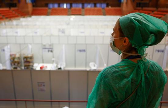 A medical worker observes installation of beds for COVID-19 patients at a sports hall in Barcelona, Spain, April 13, 2020. (Vall d'Hebron Hospital/Handout via Xinhua)