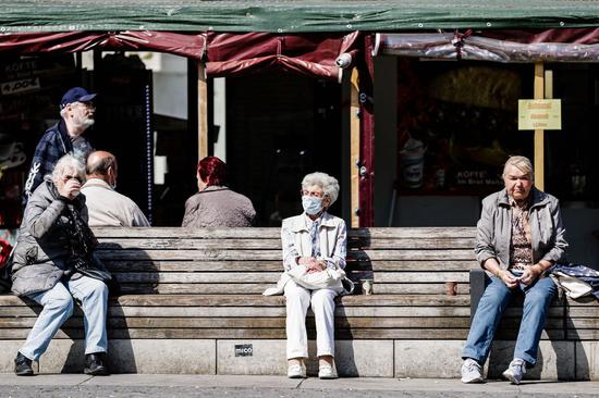 People rest on a bench with social distancing in Berlin, capital of Germany, April 11, 2020. (Photo by Binh Truong/Xinhua)