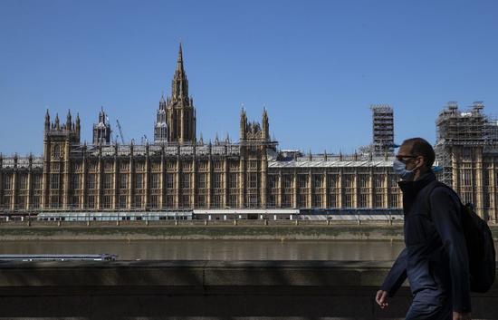 Photo taken on April 14, 2020 shows a man walking in front of the Houses of Parliament in London, Britain. (Xinhua/Han Yan)