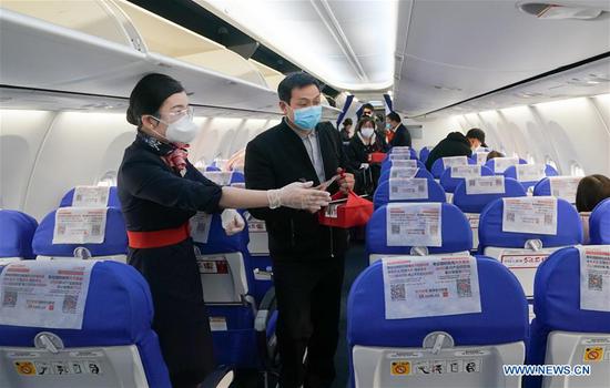 A flight attendant aboard flight MU2527 of China Eastern airlines guides a passenger at the Tianhe International Airport in Wuhan, central China's Hubei Province, April 8, 2020. (Xinhua/Cheng Min)