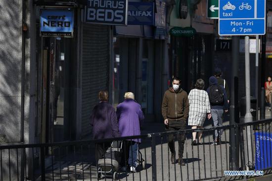 A man wearing a face mask walks on the street in London, Britain on April 21, 2020. (Xinhua/Han Yan)