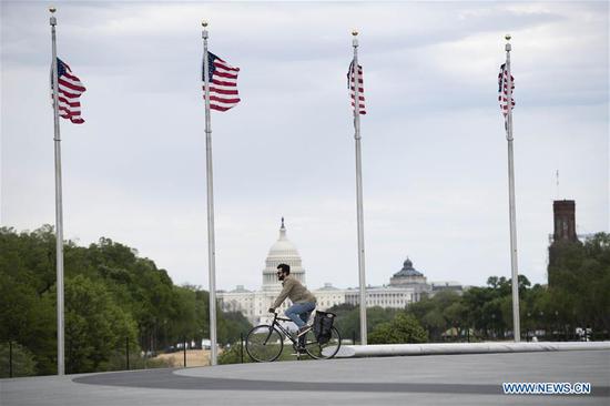 A man rides a bicycle with the U.S. Capitol Building in the background in Washington D.C., the United States, on April 21, 2020.  (Xinhua/Liu Jie)