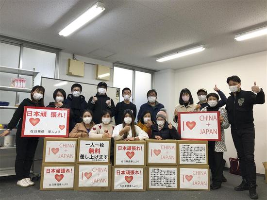 Members of a Chinese volunteer group pose for group photos before setting out to distribute masks to local people in Nagoya, Japan, February 20, 2020. (Photo/Xinhua)