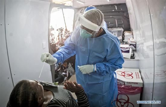 A nurse works on a testing vehicle in Johannesburg, South Africa, April 21, 2020.  (Photo by Shiraaz Mohamed/Xinhua)