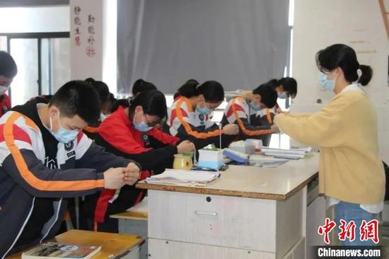 Photo provided by a local education department shows a teacher and students greeting using 