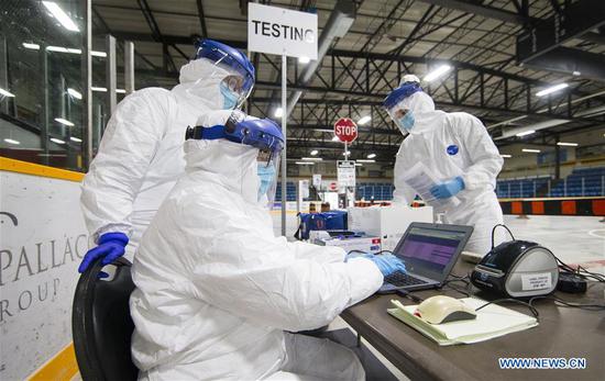 A medical worker inputs testing information at a drive-thru COVID-19 testing center in Hamilton, Ontario, Canada, on April 23, 2020. (Photo by Zou Zheng/Xinhua)