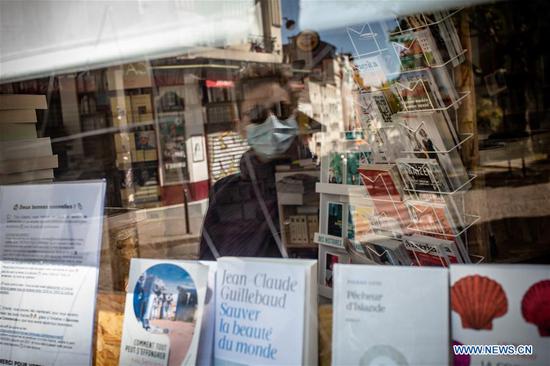 A man wearing a face mask is reflected in a window of a bookstore in Paris, France, on April 26, 2020. (Photo by Aurelien Morissard/Xinhua)