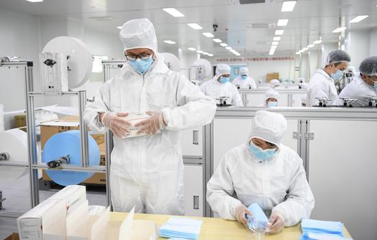 Staff members work on the face mask production line at the workshop of GAC Component Co., Ltd. in south China's Guangdong Province, Feb. 20, 2020. (Xinhua/Deng Hua)