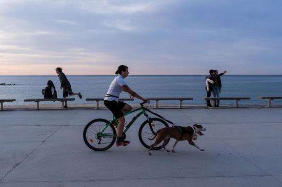 A woman cycles with a dog at the Bogatell beach in Barcelona, Spain, May 2, 2020. (Photo by Joan Gosa/Xinhua)