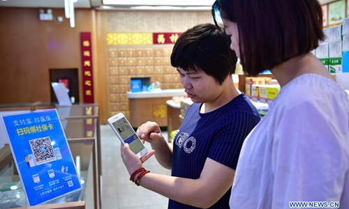 A woman scans a QR code to pay bills with electronic social security card at a 