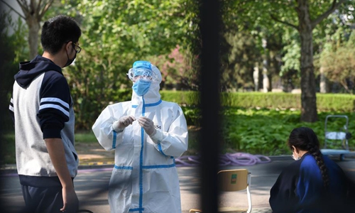 A student has her temperature taken at entrance of a high school in Beijing, April 27, 2020. (Photo/China News Service)