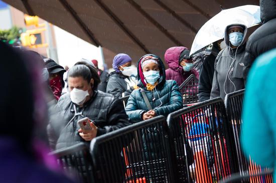 People wait to pick up food at a food bank distribution site in New York, the United States, on April 24, 2020. (Photo by Michael Nagle/Xinhua)