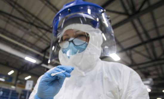 A medical worker shows a testing swab at a drive-thru COVID-19 testing center in Hamilton, Ontario, Canada, on April 23, 2020. (Photo by Zou Zheng/Xinhua)