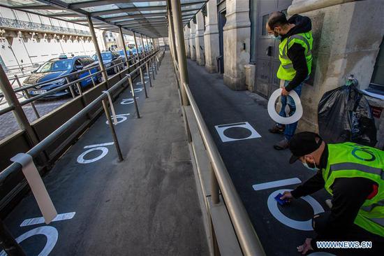 Workers put social distancing marks on the ground outside the Gare du Nord Railway Station in Paris, France, May 7, 2020. (Photo by Aurelien Morissard/Xinhua)