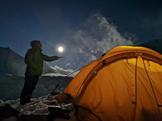 A member of the survey team takes a photo with a full moon on a campsite at Mount Qomolangma, on May 7, 2020. (Photo/Xinhua)
