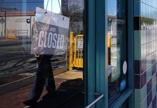 A pedestrian wearing a face mask walks past a closed shop in San Mateo City, California, the United States, April 2, 2020. (Xinhua/Wu Xiaoling)