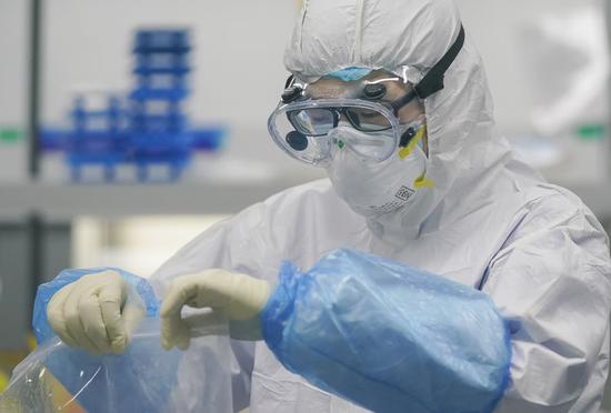 A staff member handles nucleic acid testing samples at a novel coronavirus detection lab in Wuhan, central China's Hubei Province, Feb. 22, 2020. (Xinhua/Cheng Min)