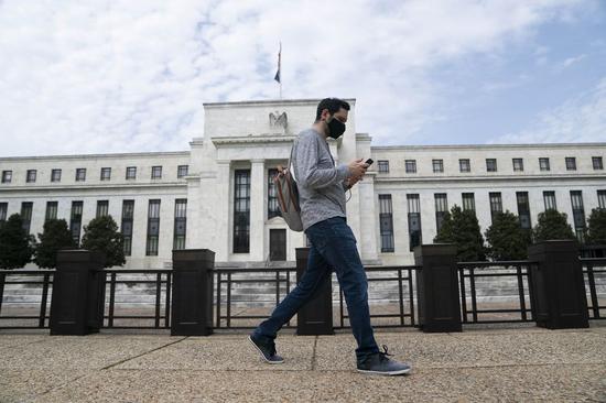 A man wearing a mask walks past the U.S. Federal Reserve building in Washington D.C., the United States, on April 29, 2020. (Xinhua/Liu Jie)