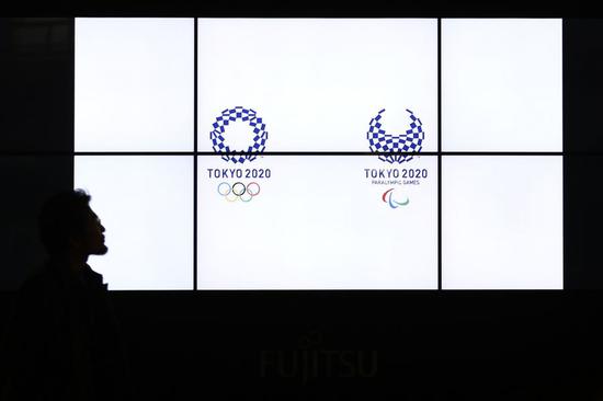 A pedestrian walks near a Tokyo 2020 Olympic Games countdown display in Shimbashi district of Tokyo, Japan, March 24, 2020. (Xinhua/Du Xiaoyi)