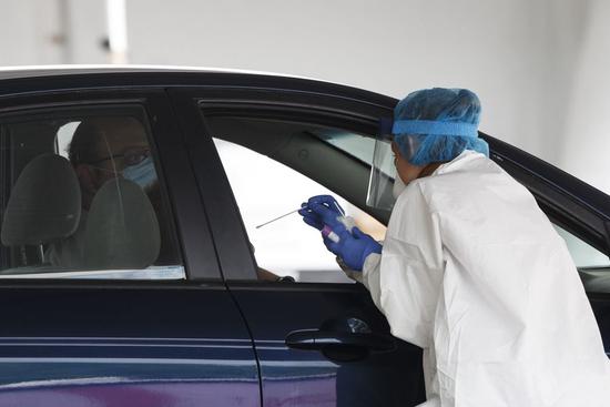 A medical worker uses a swab to take a sample at a COVID-19 drive-thru testing site in Washington D.C., the United States, on May 14, 2020. (Photo by Ting Shen/Xinhua)
