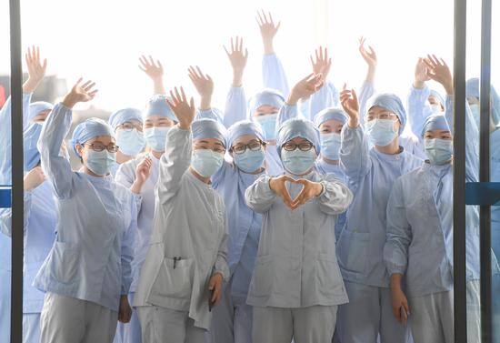 Medical staff from Wuhan No.1 Hospital gesture to bid farewell to members of a medical assistance team from Guangdong Province before their departure in Wuhan, central China's Hubei Province, March 23, 2020. (Xinhua/Chen Yehua)
