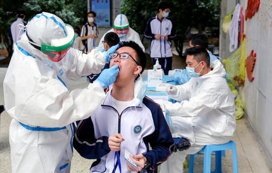 Workers in protective suits collect swabs from senior high school students for nucleic acid tests at Hubei Wuchang Experimental High School in Wuhan, Central China's Hubei province, April 30, 2020. (Photo/China News Service)