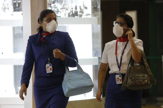 Staff members wear protective masks in the boarding area of international flights at the Jorge Chavez International Airport, in the constitutional province of Callao, Peru, on March 6, 2020. (Photo by Mariana Bazo/Xinhua)