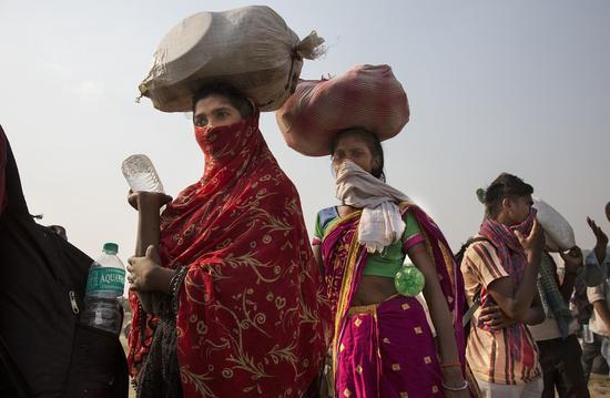 Stranded migrant workers line up to board buses heading for their hometowns during extended lockdown to curb COVID-19 in Ghaziabad, India, May 18, 2020. (Xinhua/Javed Dar)