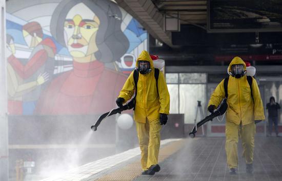 Municipal employees wearing protective suits disinfect a railway station in Moscow, Russia, May 19, 2020. (Photo by Alexander Zemlianichenko Jr/Xinhua)