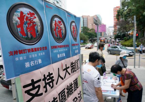 A resident signs in a street campaign in support of national security legislation for Hong Kong Special Administrative Region in Hong Kong, China, May 23, 2020. (Xinhua/Li Gang)