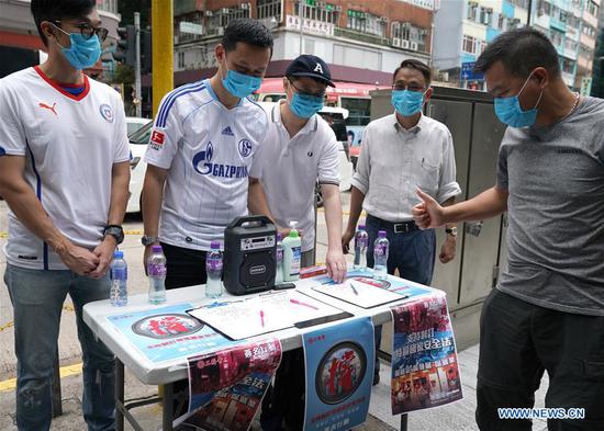 A resident signs in a street campaign in support of national security legislation for Hong Kong Special Administrative Region (HKSAR) in Hong Kong, south China, May 23, 2020. (Xinhua/Li Gang)