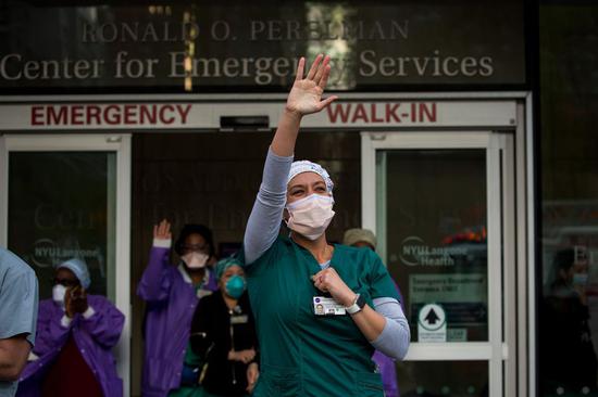 Samantha Giambalvo, a traveling nurse from Alabama who has been working in New York since April 6, and other colleagues wave as firefighters and residents show appreciation for healthcare workers at NYU Langone Medical Center amid the COVID-19 outbreak in New York, the United States, May 9, 2020. (Photo by Michael Nagle/Xinhua)