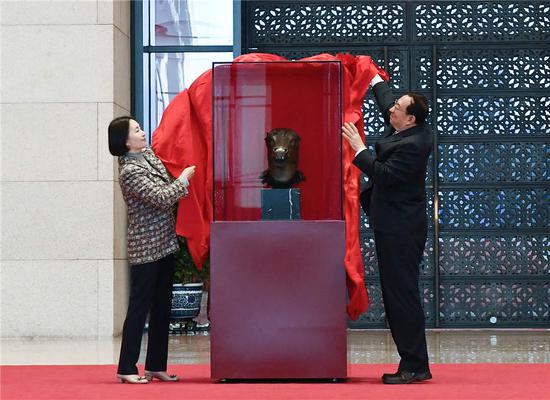 Pansy Ho Chiu-king (left), Stanley Ho's daughter, and Luo Shugang, Minister of Culture and Tourism, lift the curtain for the newly returned statue at National Museum of China on Nov 13, 2019.  (Photo/Xinhua)